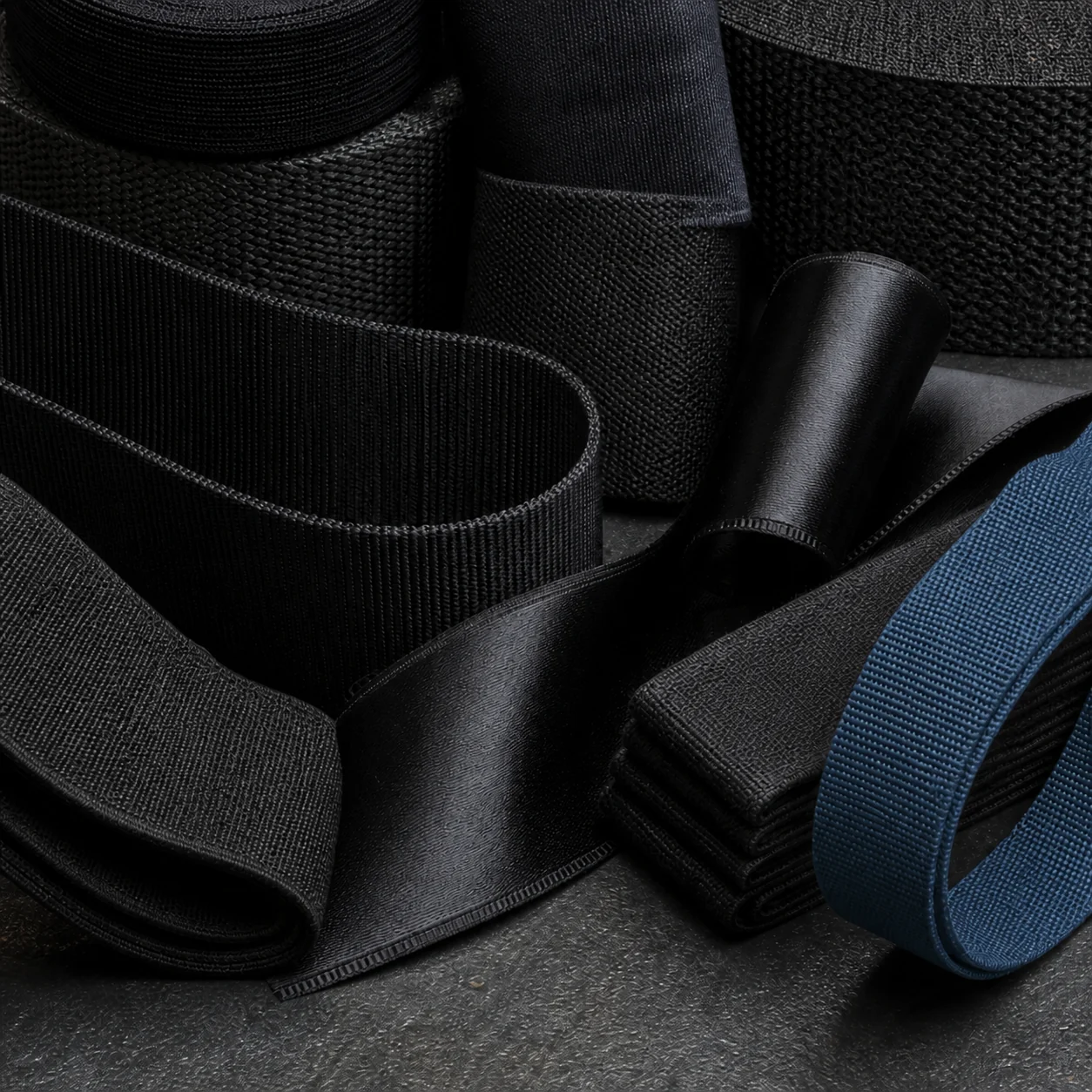 Layered black woven tapes and technical ribbons showing contrasting fibres and selvedges